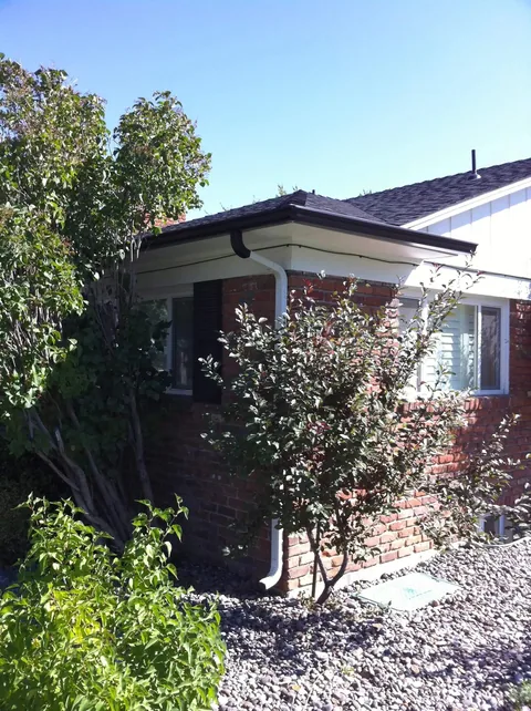 Classic Reno brick bungalow with brown aluminum gutter and white downspout