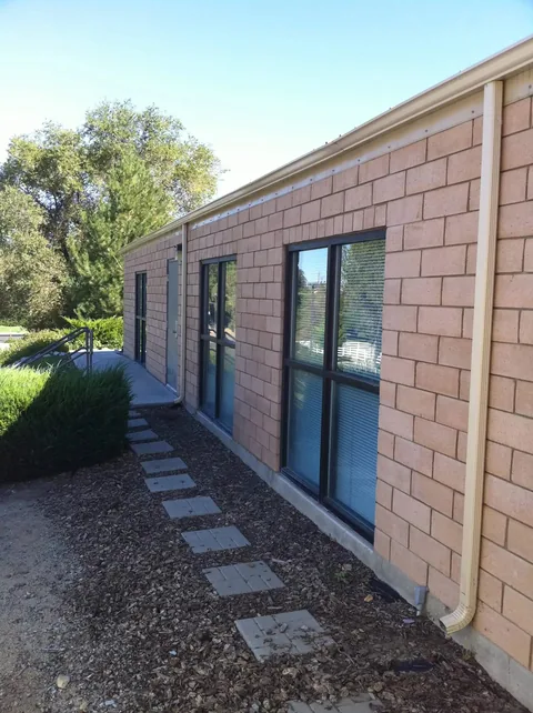 Brick commercial building with full-length aluminum gutter, wraparound downspouts