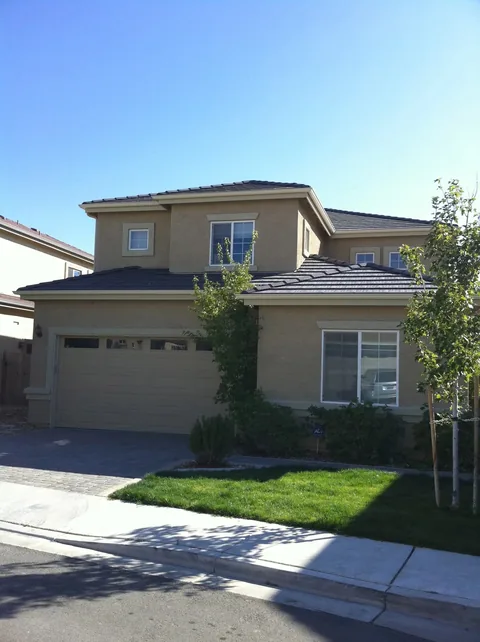 Contemporary two-story tan stucco home with wraparound gutter system