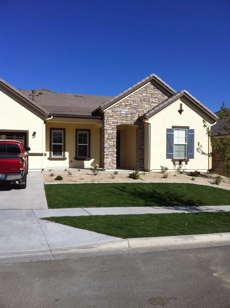 Stucco and stone craftsman home, concealed dark gutter on tile roof
