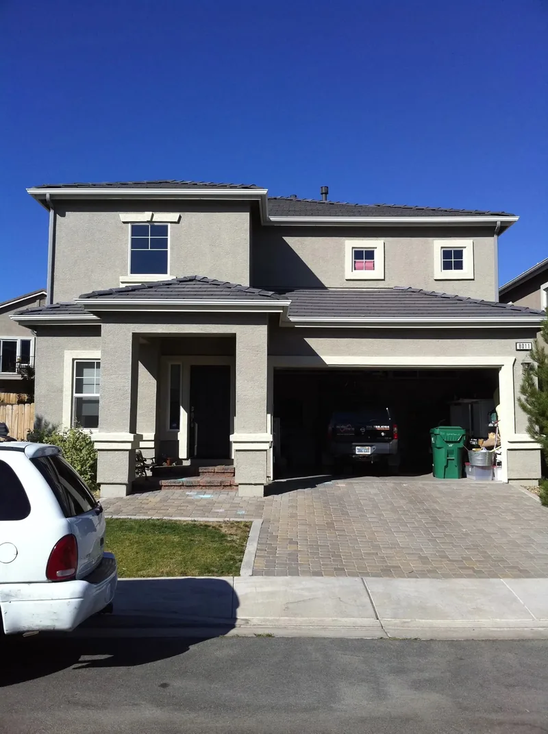 Stucco family home with paver driveway and clean gutter profile